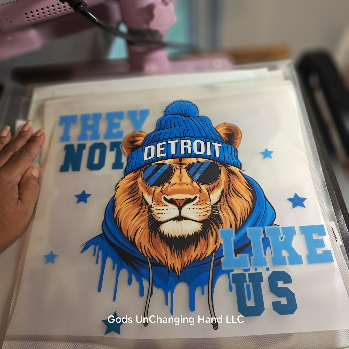 Close-up of They Not Like Us lion design with Detroit beanie and sunglasses